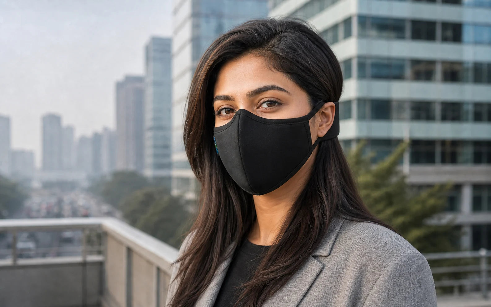 Adult woman wearing the Black OxiClear N99 anti-pollution mask without a valve and its detachable headband in an urban setting